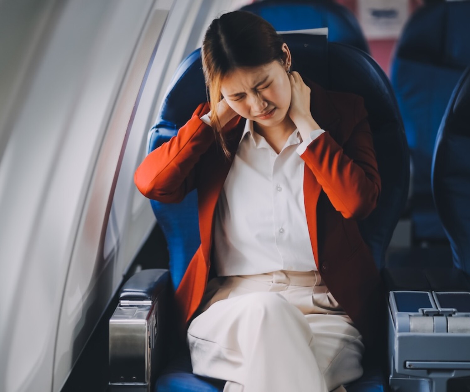 Photo of a frustrated woman sitting on an airplane with her head in her hands. Asian woman sitting in a seat in airplane